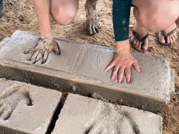 putting hand prints in clay adobe bricks